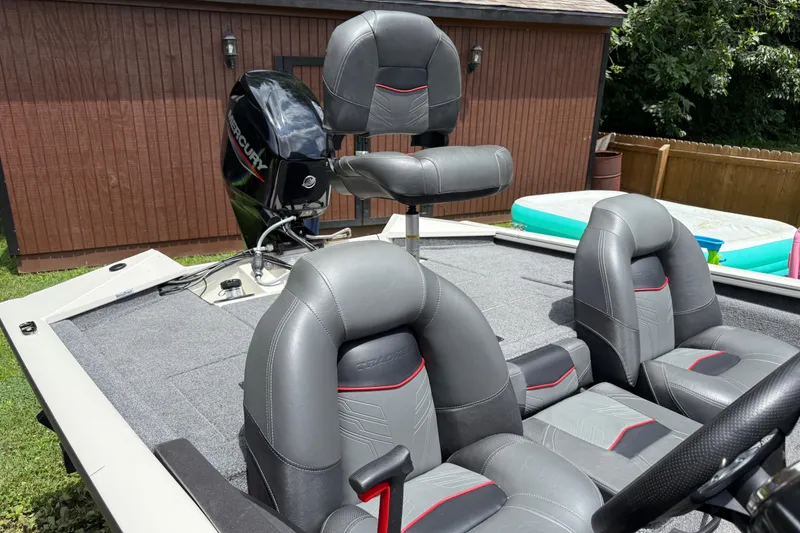 Slide: The Image of 2024 Bass Tracker Pro 17 boat interior with Mercury engine, featuring gray and red seating. - 6