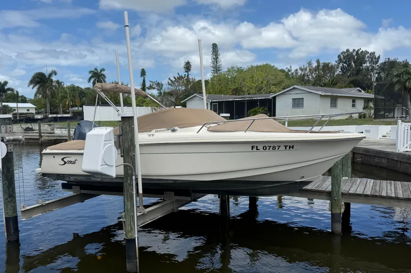 The Image of 2017 Scout 210 Dorado boat docked, covered, with outboard motor, in a residential marina. - 0