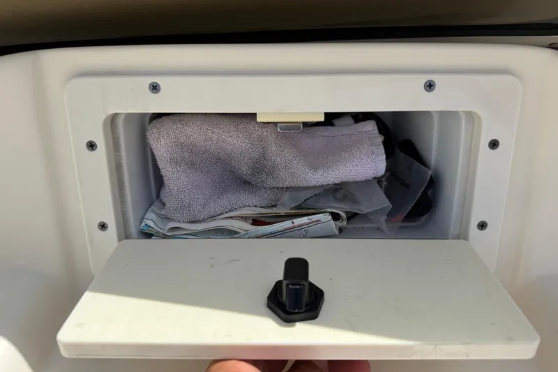 Slide: The Image of Storage compartment on a 2017 Scout 210 Dorado boat, containing a towel and miscellaneous items. - 19