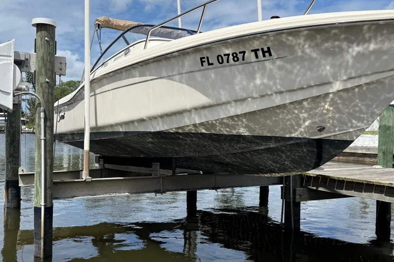 Slide: The Image of 2017 Scout 210 Dorado boat on lift, reflecting sunlight on water. - 2