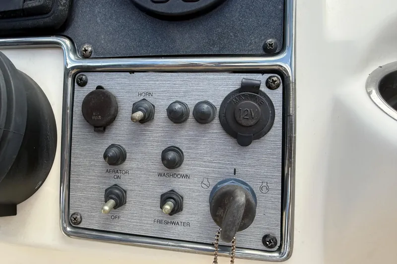 Slide: The Image of Control panel of a 2017 Scout 210 Dorado boat with switches and 12V outlet. - 26
