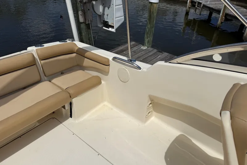 Slide: The Image of 2017 Scout 210 Dorado boat interior with beige seating near a dock. - 8