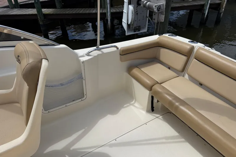 Slide: The Image of 2017 Scout 210 Dorado boat interior with beige seating and dock background. - 9