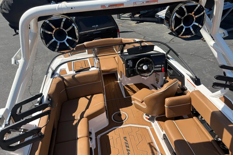 Slide: The Image of 2023 Moomba Kaiyen boat interior with tan seating, modern dashboard, and large speakers. - 13