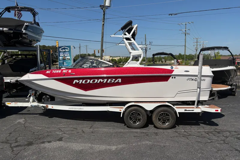 Slide: The Image of 2023 Moomba Kaiyen boat on trailer, red and white design, parked outdoors. - 2