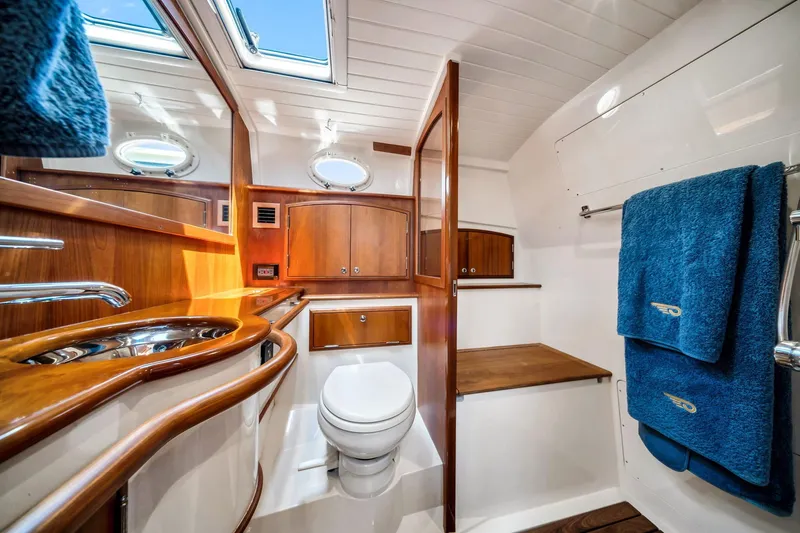 Slide: The Image of Luxurious bathroom interior of 2020 Hinckley Picnic Boat 40 with wood accents and blue towels. - 12
