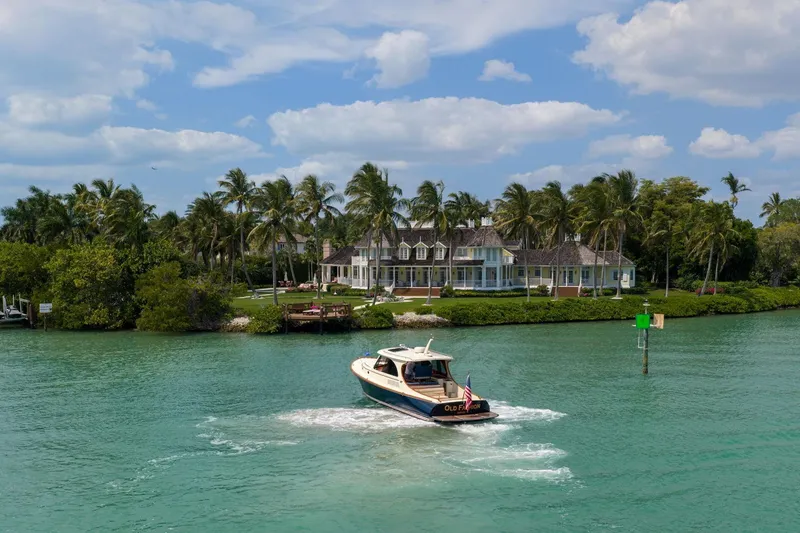 Slide: The Image of Hinckley Picnic Boat 40 cruising on turquoise waters near a luxurious waterfront estate, 2020 model. - 17