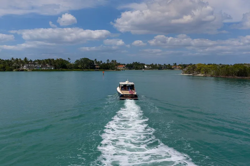Slide: The Image of 2020 Hinckley Picnic Boat 40 cruising on a serene, tropical waterway under a partly cloudy sky. - 18