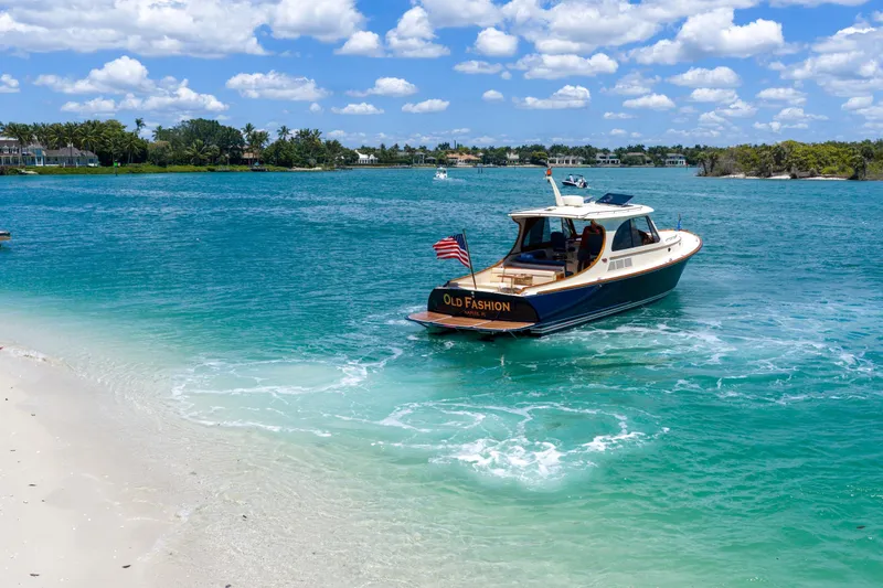Slide: The Image of 2020 Hinckley Picnic Boat 40 cruising on a scenic waterway under a clear blue sky. - 19