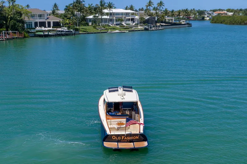 Slide: The Image of Hinckley Picnic Boat 40, 2020 model, cruising near a sandy beach under a blue sky. - 20