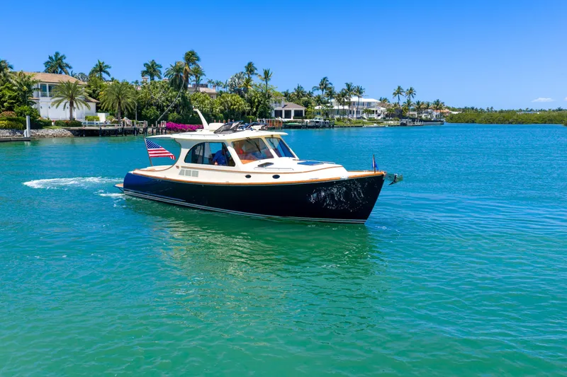 Slide: The Image of Hinckley Picnic Boat 40 cruising on a serene waterway, surrounded by luxury homes. - 21