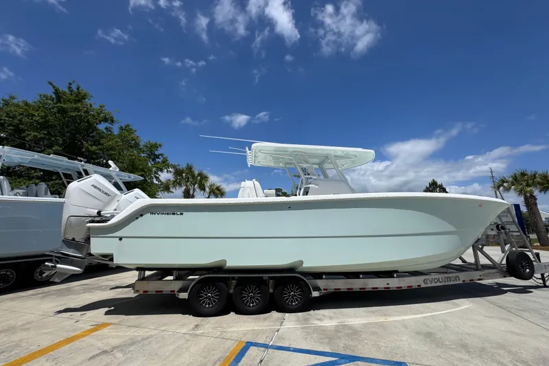 Slide: The Image of 2024 Invincible 33 Catamaran on trailer under clear blue sky. - 11