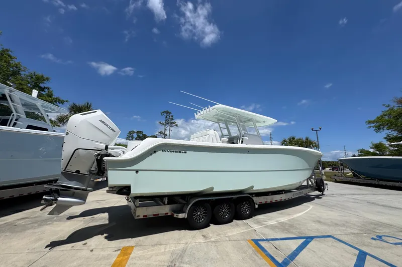 Slide: The Image of 2024 Invincible 33 Catamaran with Mercury engines on a trailer under a clear blue sky. - 12