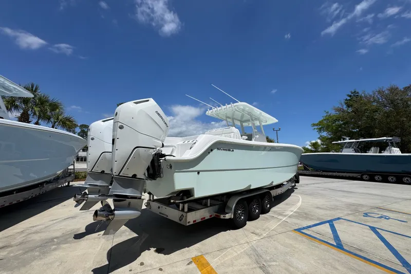 Slide: The Image of 2024 Invincible 33 Catamaran on trailer, featuring dual outboard engines, under a clear blue sky. - 13