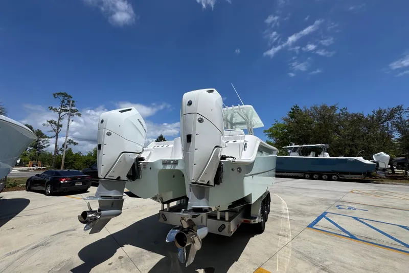 Slide: The Image of 2024 Invincible 33 Catamaran with dual outboard motors in a sunny parking lot. - 14