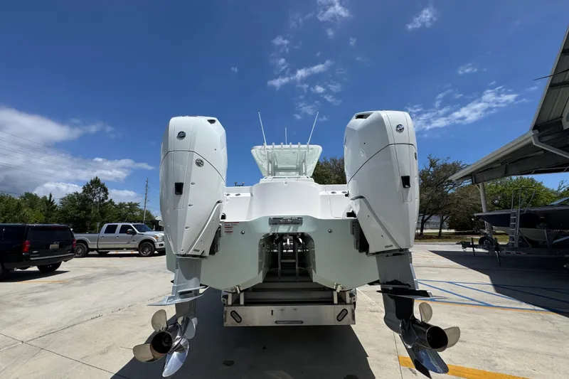Slide: The Image of 2024 Invincible 33 Catamaran with dual outboard engines, parked outdoors under a clear sky. - 15