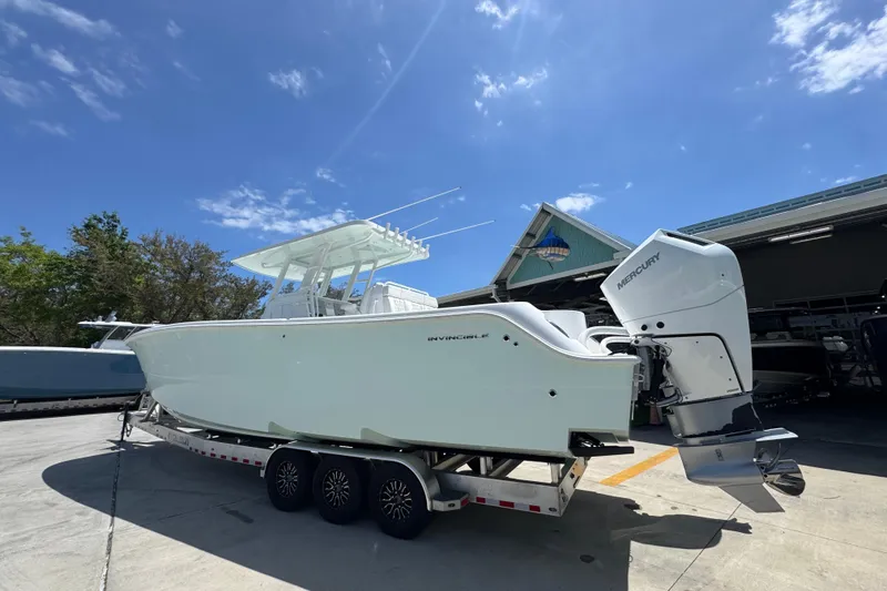 Slide: The Image of 2024 Invincible 33 Catamaran on trailer, featuring Mercury outboard engines, parked outdoors. - 17