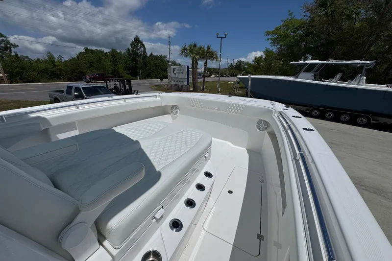 Slide: The Image of 2024 Invincible 33 Catamaran with white seating and sleek design, parked outdoors. - 20