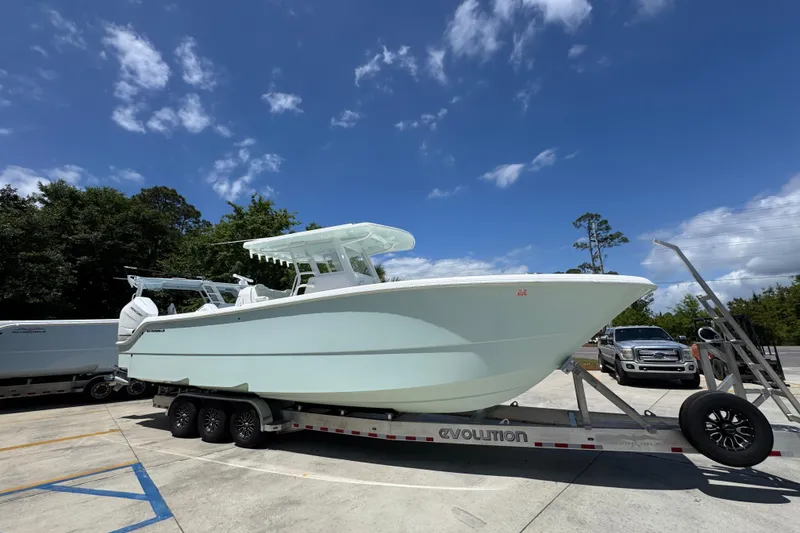 Slide: The Image of 2024 Invincible 33 Catamaran on trailer under blue sky, parked in lot. - 9