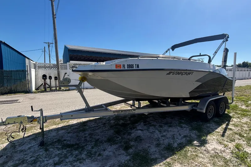 Slide: The Image of 2023 Starcraft SVX 191 OB boat on trailer, parked outdoors under clear blue sky. - 21