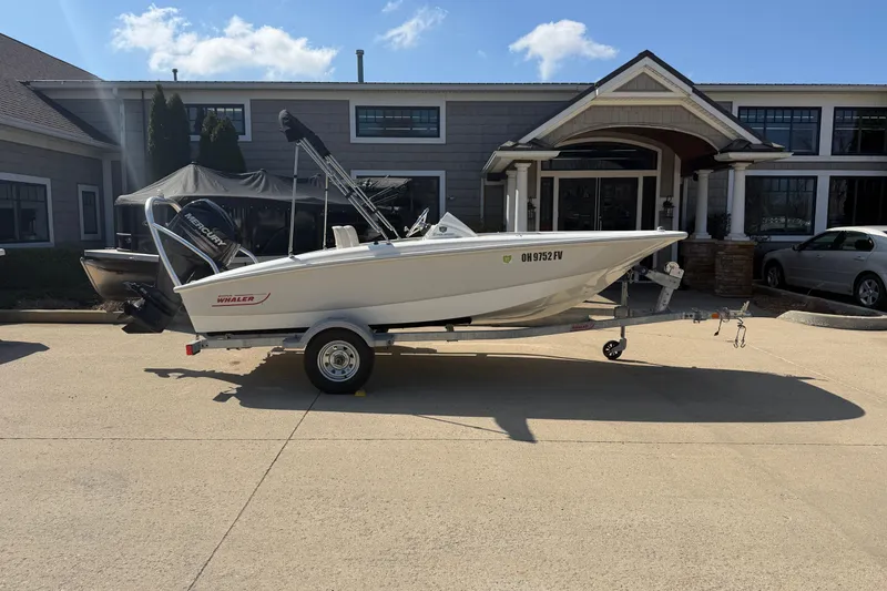 The Image of 2018 Boston Whaler 150 Super Sport boat on trailer, parked in front of a house. - 1