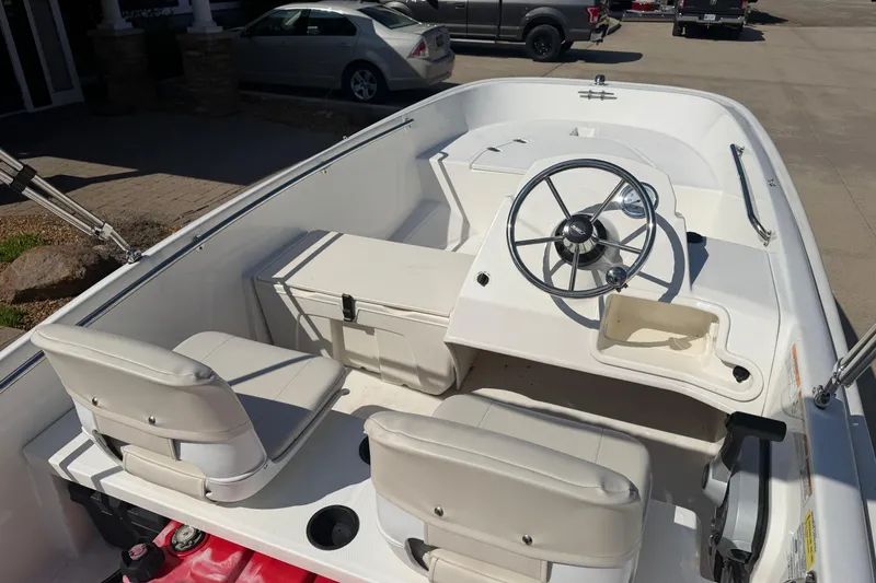 Slide: The Image of 2018 Boston Whaler 150 Super Sport boat interior with steering wheel and seating. - 7
