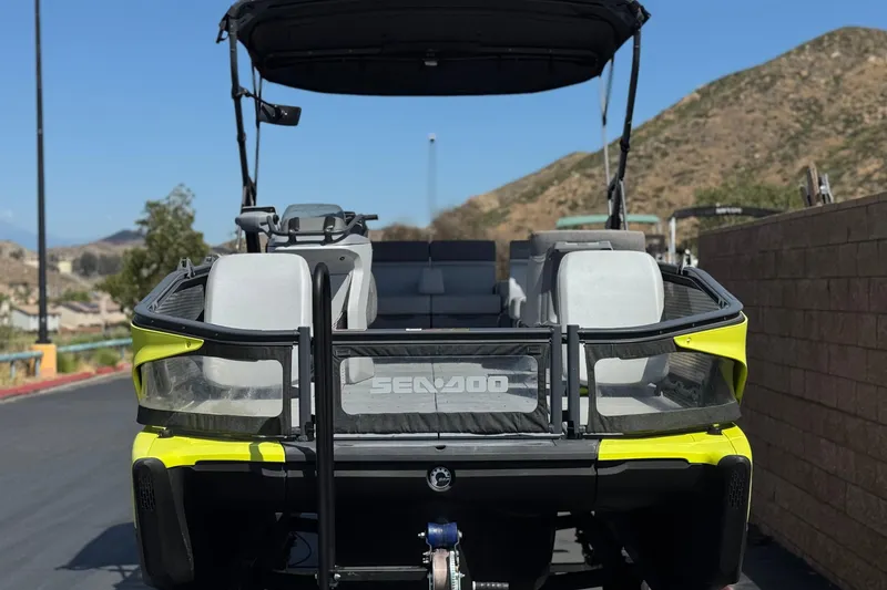 Slide: The Image of 2022 Sea-Doo Switch Sport 21 pontoon boat, rear view, parked on a sunny day. - 2