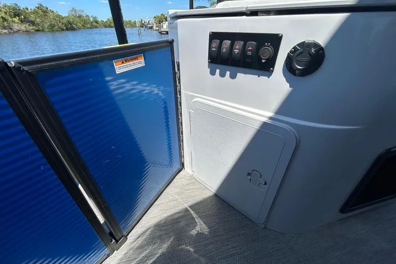 Slide: The Image of Control panel and storage on 2022 Godfrey Sweetwater 2286FS boat, near water. - 108