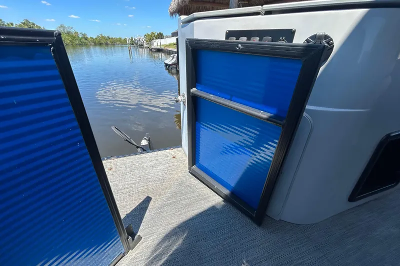 Slide: The Image of 2022 Godfrey Sweetwater 2286FS boat with open blue gate, overlooking calm water. - 109