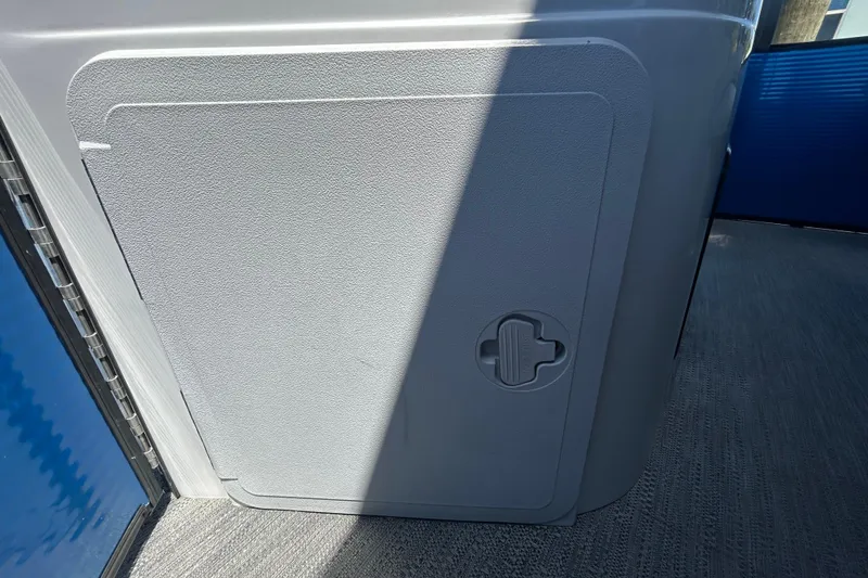 Slide: The Image of Storage compartment on a 2022 Godfrey Sweetwater 2286FS boat, featuring a textured gray door. - 110