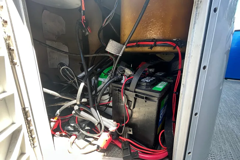 Slide: The Image of Battery compartment of a 2022 Godfrey Sweetwater 2286FS boat with visible wiring. - 112
