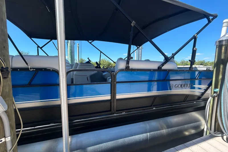 Slide: The Image of 2022 Godfrey Sweetwater 2286FS pontoon boat docked with blue exterior and canopy. - 17