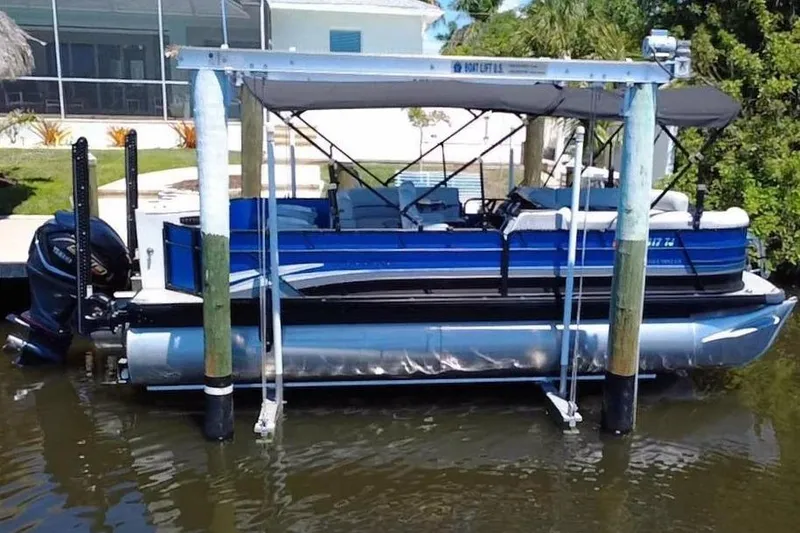 Slide: The Image of 2022 Godfrey Sweetwater 2286FS pontoon boat on a lift by the water. - 2