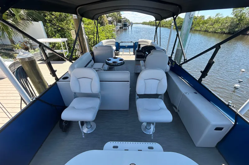 Slide: The Image of 2022 Godfrey Sweetwater 2286FS pontoon boat interior with seating and canopy on a scenic river. - 26