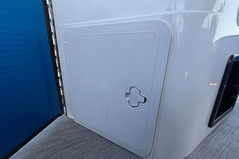 Slide: The Image of Storage compartment on a 2022 Godfrey Sweetwater 2286FS boat, featuring a secure latch. - 55