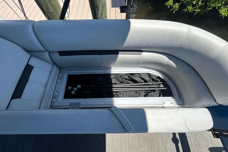 Slide: The Image of 2022 Godfrey Sweetwater 2286FS boat seat storage compartment with fishing gear inside. - 56