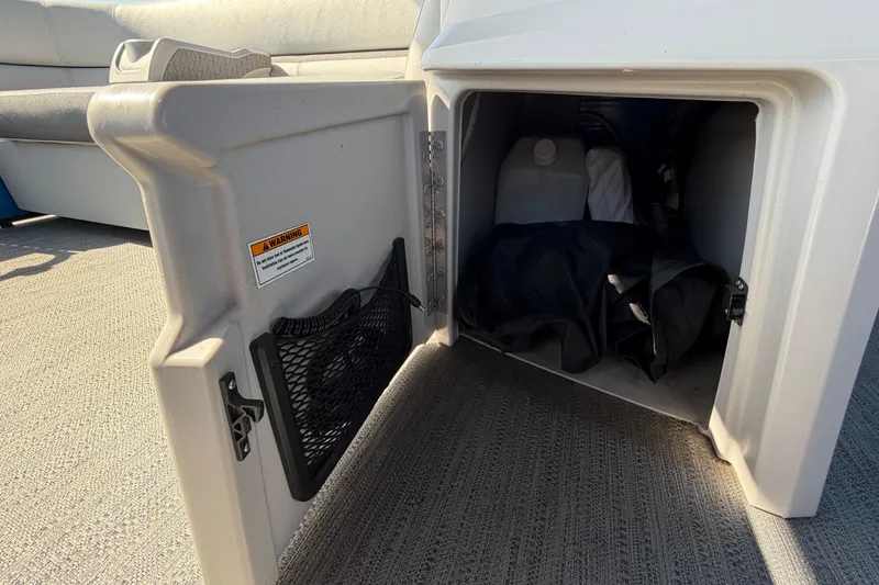 Slide: The Image of Storage compartment on 2022 Godfrey Sweetwater 2286FS boat, featuring safety warning label. - 22
