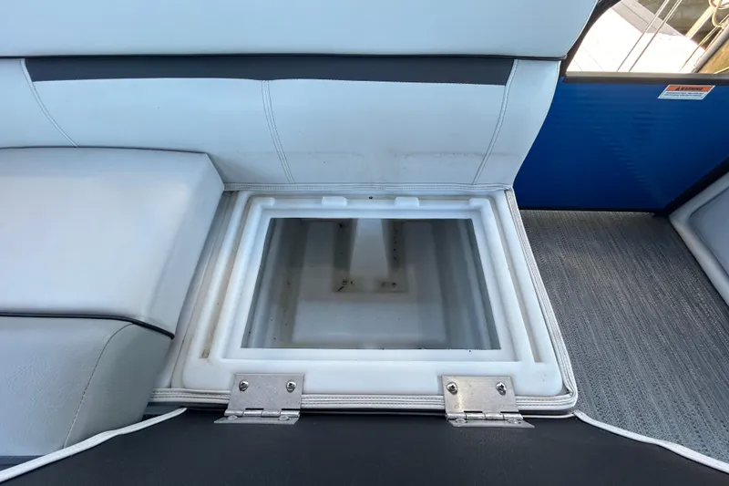 Slide: The Image of Open storage compartment on 2022 Godfrey Sweetwater 2286FS boat with cushioned seating. - 75