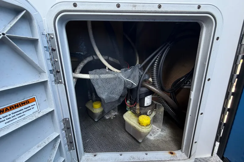 Slide: The Image of 2022 Godfrey Sweetwater 2286FS compartment with cables, fluid containers, and warning label. - 61