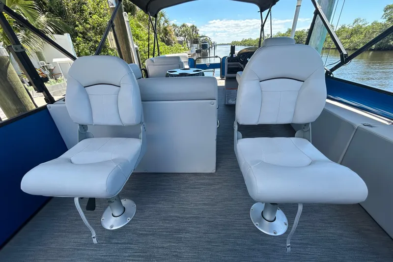 Slide: The Image of Interior of 2022 Godfrey Sweetwater 2286FS boat with two white seats and scenic river view. - 86