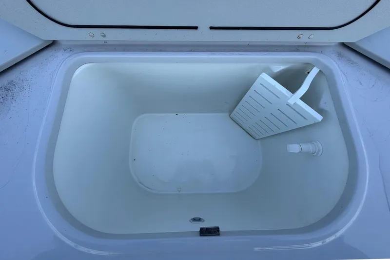 Slide: The Image of An open storage compartment on a boat with a white insert and a drain. - 47
