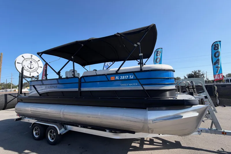 The Image of 2022 Godfrey Sweetwater 2286FS pontoon boat on trailer, displayed at a boat sale event. - 0