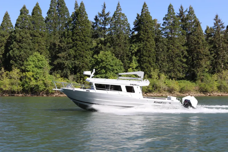 Slide: The Image of 2026 KingFisher 3425 GFX Offshore boat cruising on a scenic lake with forest backdrop. - 2