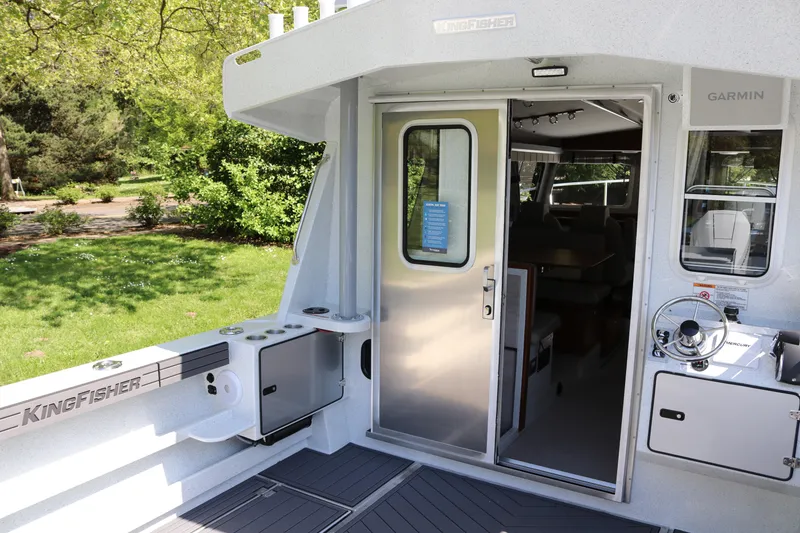 Slide: The Image of 2026 KingFisher 3425 GFX Offshore boat interior with open door and steering wheel. - 3