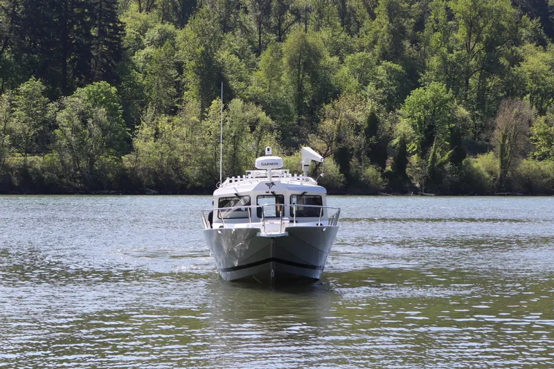 Slide: The Image of KingFisher 3425 GFX Offshore boat on a serene lake, surrounded by lush greenery. - 1