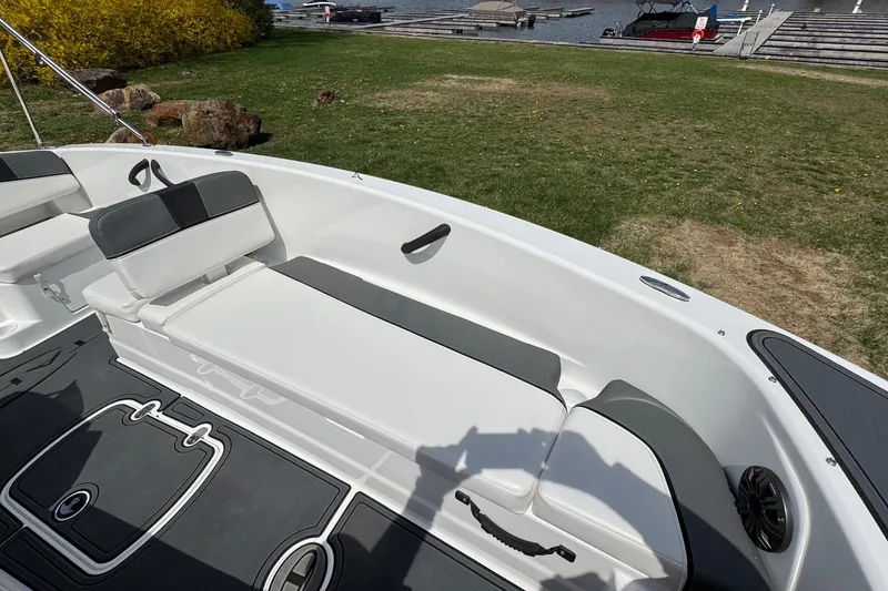 Slide: The Image of 2025 Tahoe T18 boat interior with white and gray seating near a lakeside dock. - 12