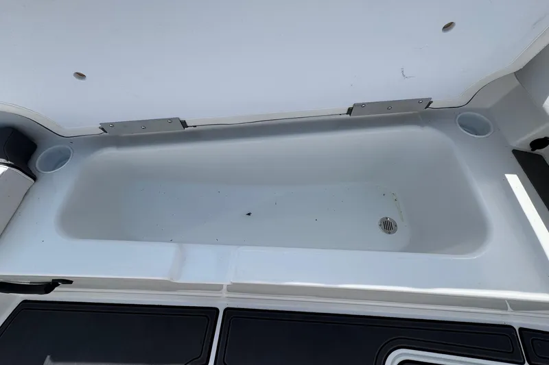 Slide: The Image of Open storage compartment in 2025 Tahoe T18 boat, featuring a drain plug. - 13