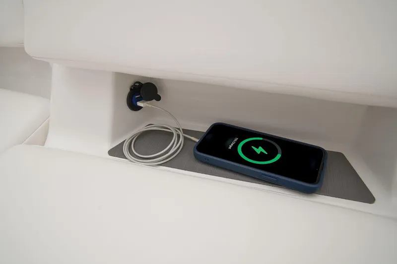 Slide: The Image of Manufacturer Provided Image: Charging phone in Tahoe T18 2025 boat compartment with USB port and cable. - 16