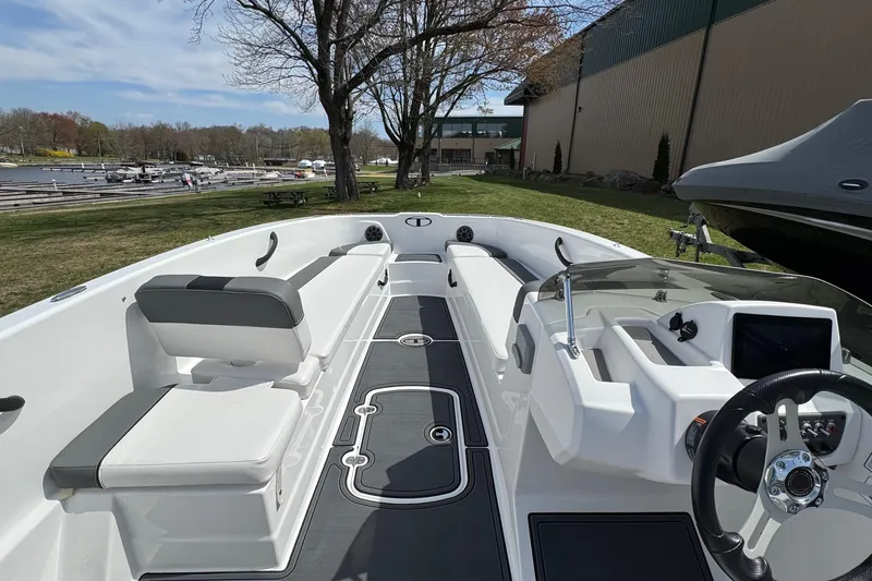Slide: The Image of 2025 Tahoe T18 boat interior with seating and steering wheel, docked near a marina. - 6