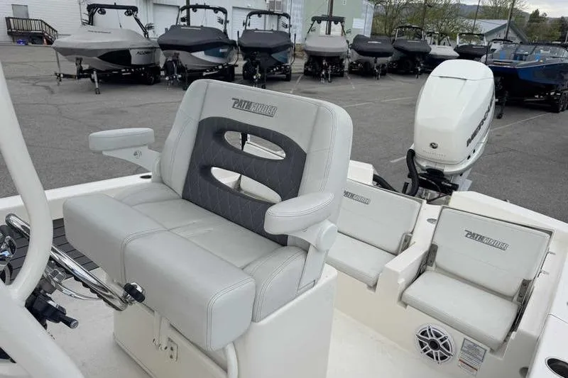 Slide: The Image of 2023 Pathfinder 2600 HPS boat interior with cushioned seating and motor, parked outdoors. - 17